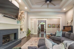 A spacious living room with a fireplace, a large sofa, and a ceiling fan.