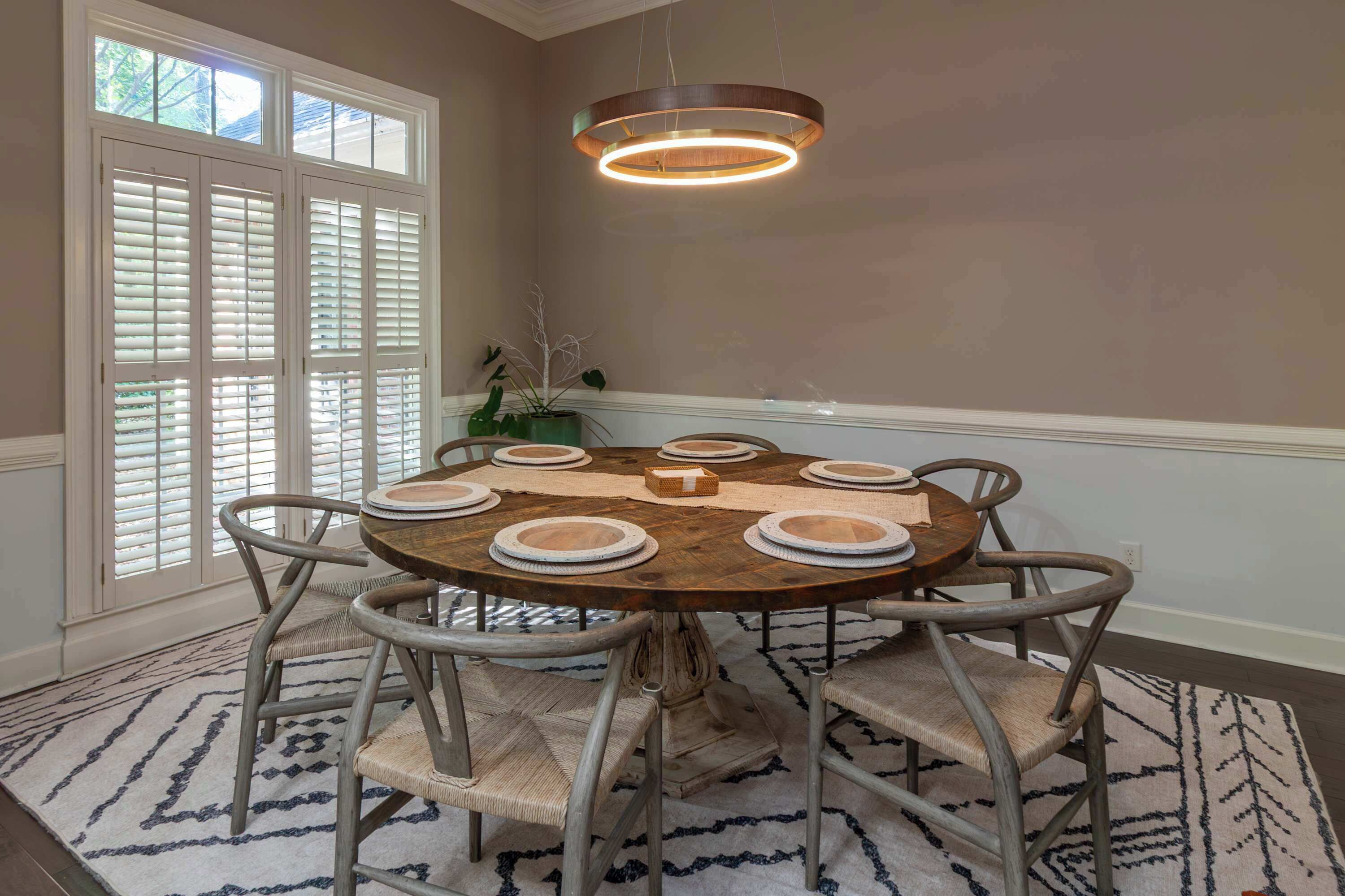 Un coin repas comprenant une table ronde, six chaises et un luminaire suspendu.