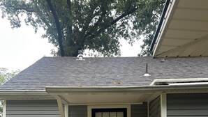 A residential house with a grey siding exterior, a black-framed front door with decorative glass panels, a small brick step leading to the entrance, and a metal lantern on the wall. - Comfortable Charming Convenient in Covington TN (Covington)
