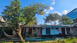 Un edificio residencial con un porche delantero, una hamaca y un pequeño jardín.