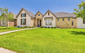 A two-story house with a stone facade, a front porch, and a well-maintained lawn.