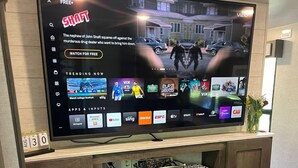 Een flatscreen-tv bevestigd aan een houten tv-meubel met een open haard eronder.