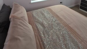 Un dormitorio con cama, ventana con persianas, cómoda y toma de corriente.