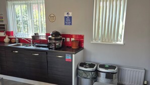 Una cocina compacta con un lavamanos, un hervidor y dos cubos de basura.