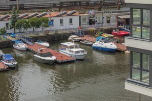 A marina with various boats docked, a building with a sign, and a clear view of the water. - Stylish Apartment with River Views | Garage (Szczecin)