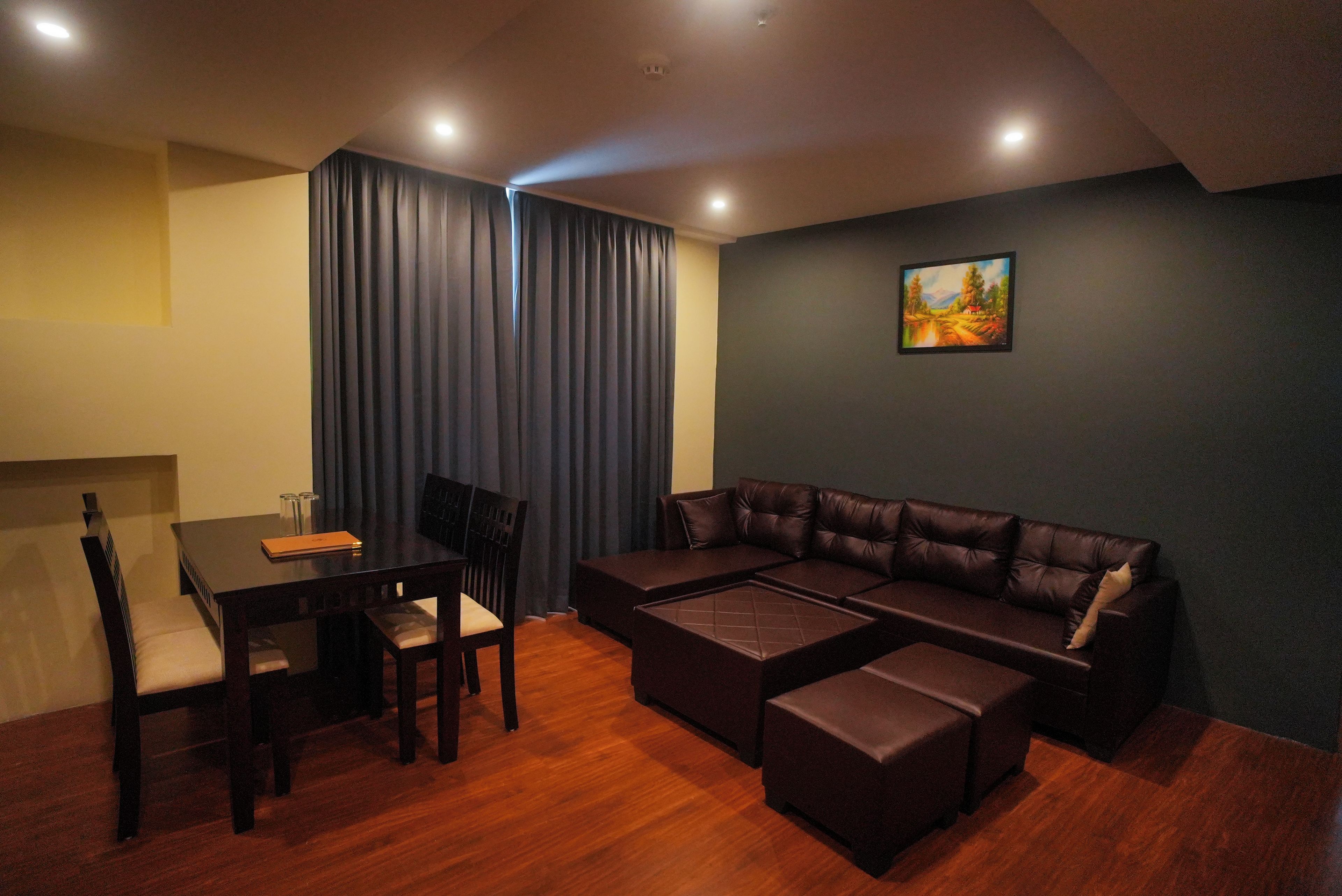A modern living room with a sectional sofa, a dining table with chairs, and a painting on the wall.