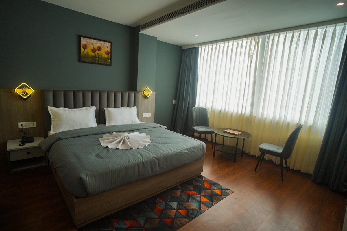 Una habitación de hotel con una cama grande, un escritorio, una silla y una ventana con cortinas.