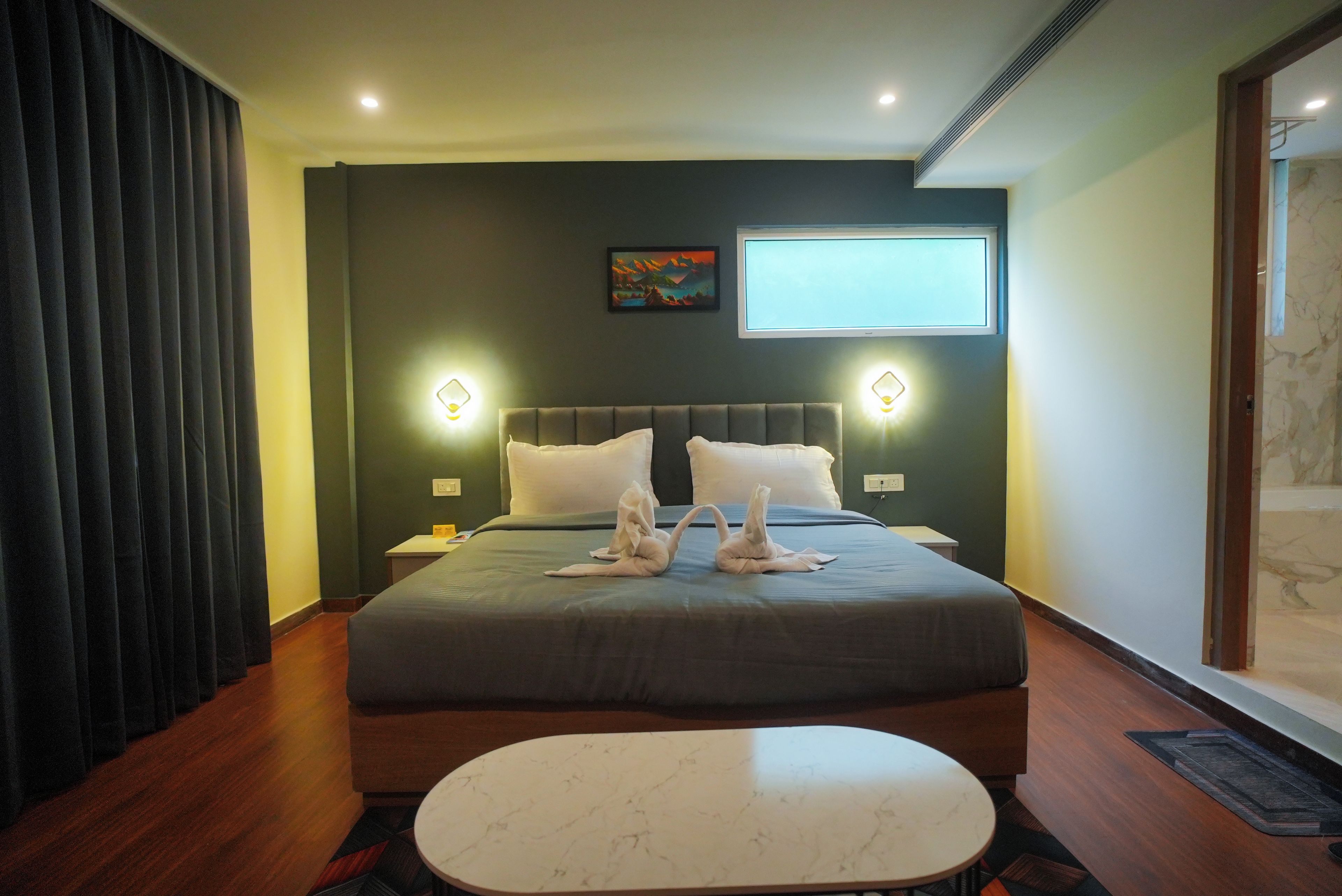 Habitación de hotel con una cama grande, dos lámparas fijadas a la pared, un televisor de pantalla plana y un cuadro en la pared.
