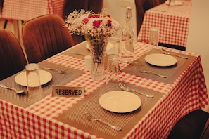 Una mesa con mantel a cuadros, un jarrón con flores y un cartel que dice 'RESERVED'.