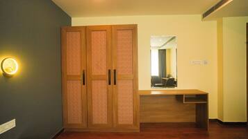 A room with a wooden wardrobe, a desk, and a mirror.