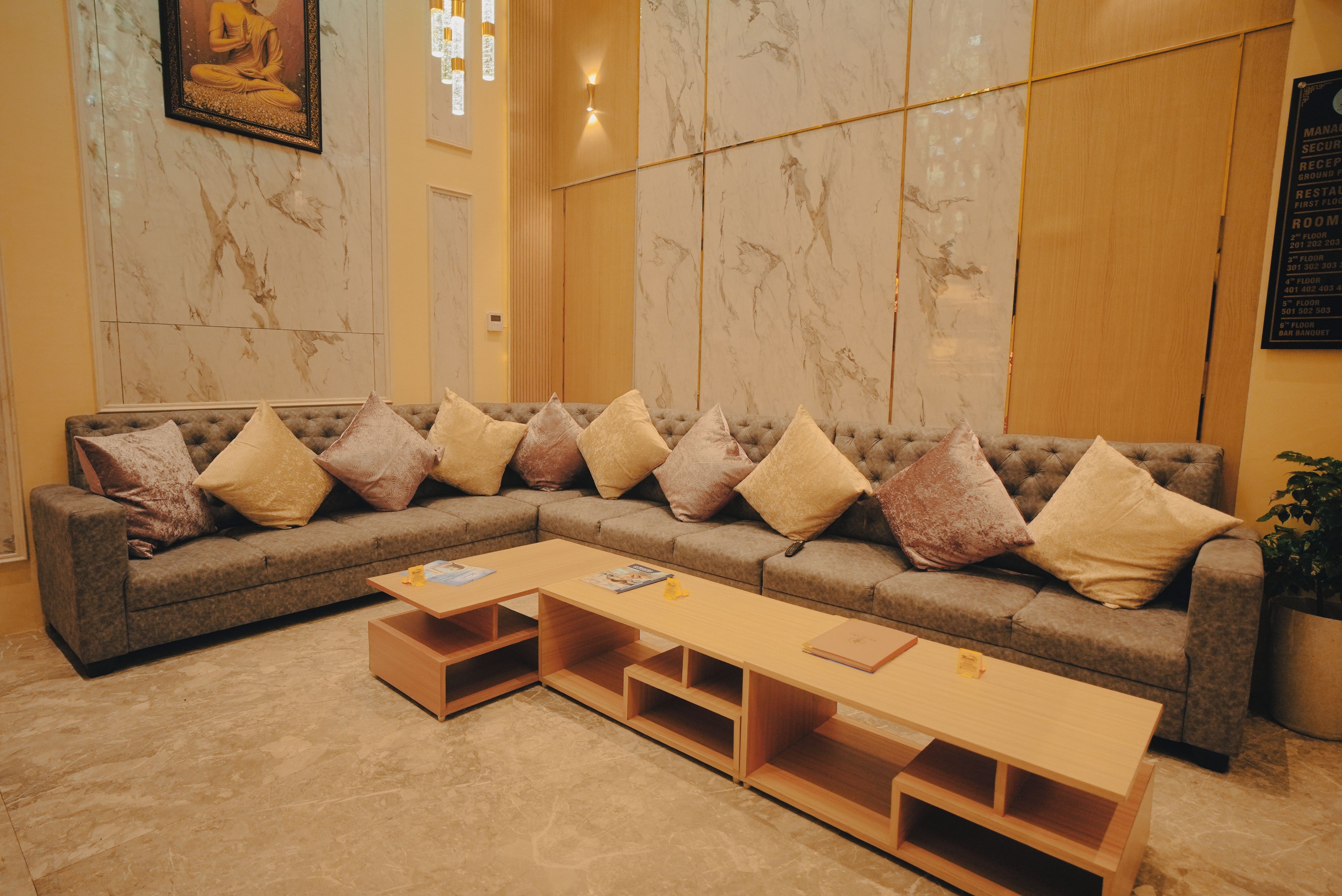 Un moderno vestíbulo de hotel con un amplio sofá modular, una mesa de centro de madera y paredes de mármol.