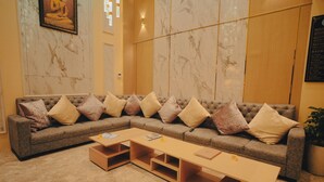A modern hotel lobby with a large sectional sofa, a wooden coffee table, and marble walls. - Meraki Hotels & Resorts Sikkim (Gangtok)