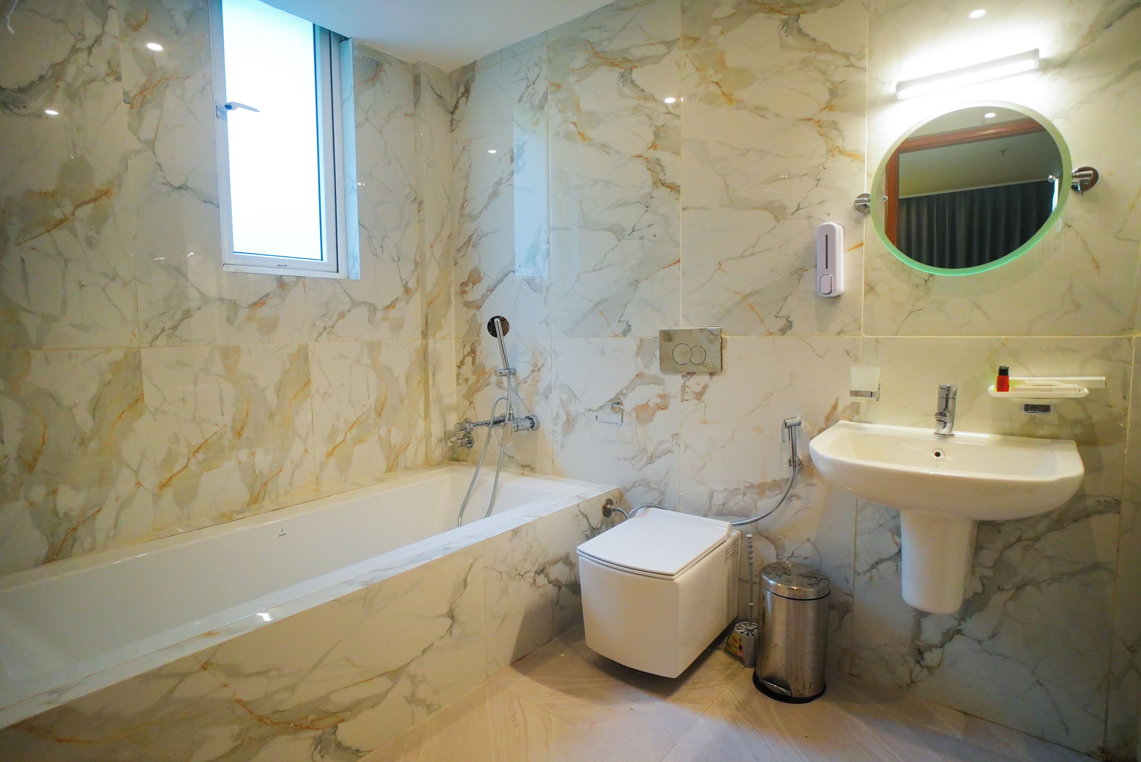 A bathroom with a bathtub, a sink, a mirror, and a window.