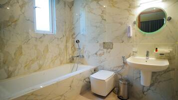 A bathroom with a bathtub, a sink, a mirror, and a window.