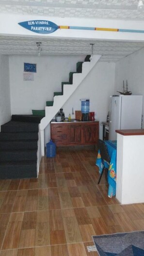 A staircase leading to a landing with a water dispenser and a refrigerator on the landing.
