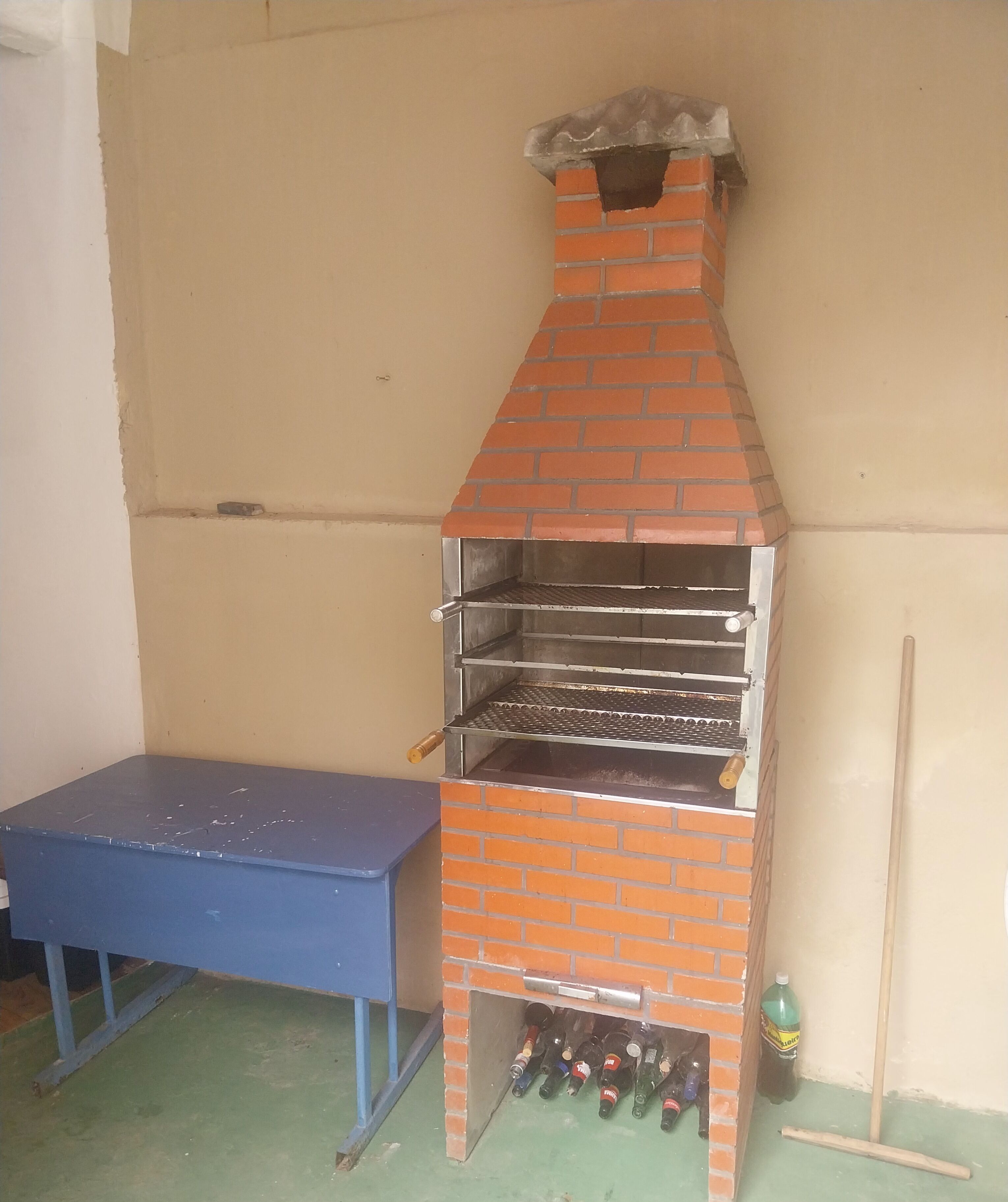 A brick-built outdoor grill with multiple shelves and a table nearby.