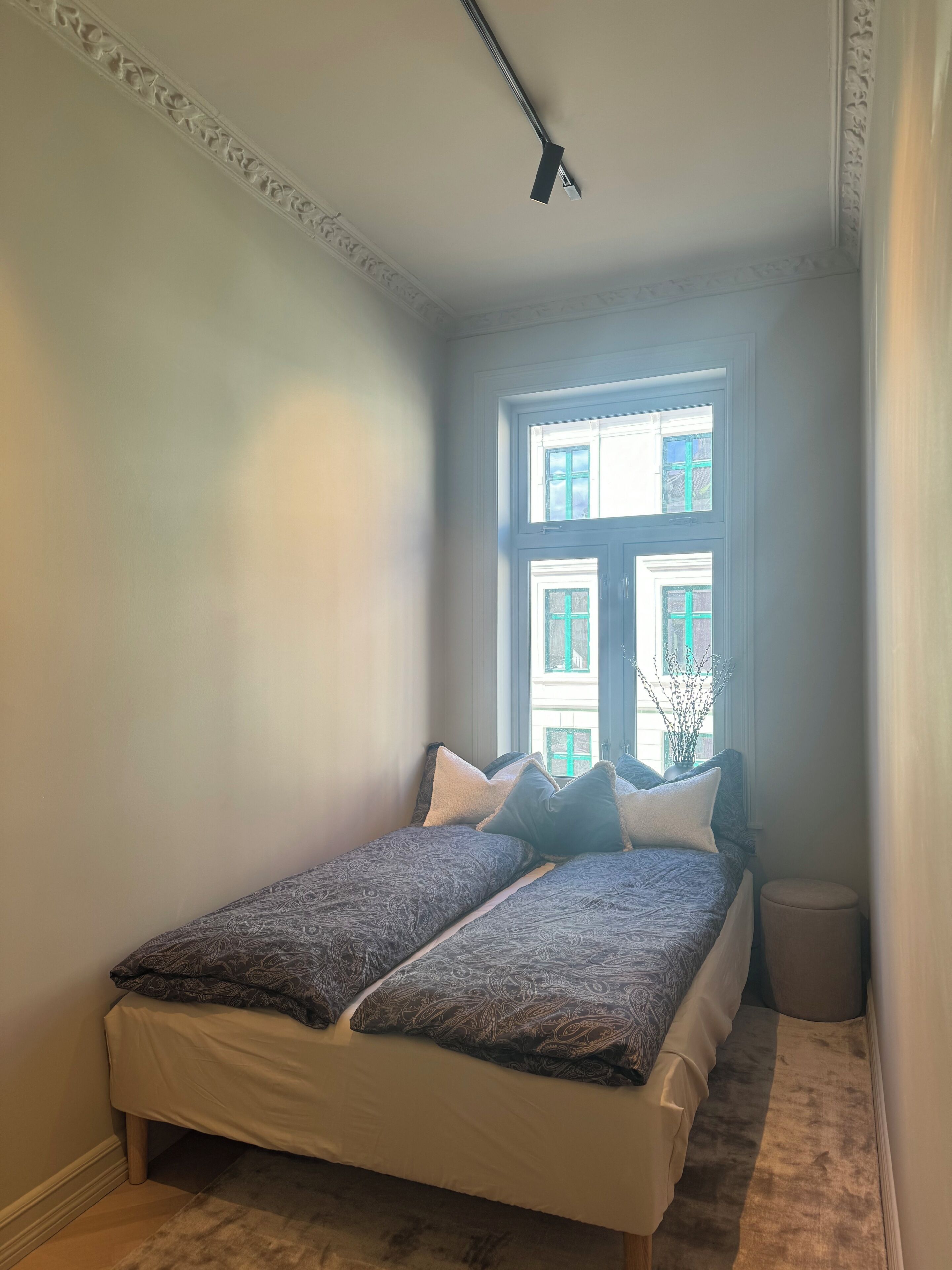 A room with a bed, a window, and a ceiling light.