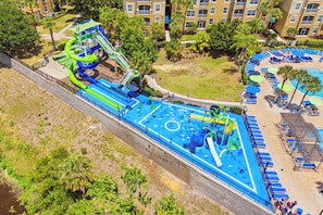 Ein Luftbild eines Wasserparks mit einem großen Schwimmbecken, Rutschen und einer umliegenden Liegeflächen.
