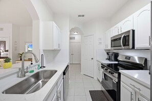A modern kitchen with white cabinetry, stainless steel appliances, and a central island. - The Happily Ever After Hideaway (Kissimmee)