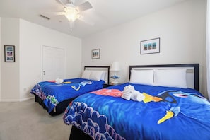 Ein Hotelzimmer mit zwei Betten, einem Deckenventilator und Kunstwerken an den Wänden.