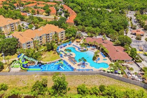 Eine Vogelperspektive zeigt einen luxuriösen Komplex mit großem Pool, Wasserpark und mehreren Gebäuden mit roten Dächern.