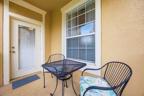 A covered patio area with a door, two chairs, and a table. - The Happily Ever After Hideaway (Kissimmee)