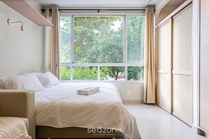 A bedroom with a large window, a bed, a chair, and a wardrobe. - Modern Studio 110 m From Lagoa da Conceicao Bdr523 (Florianópolis)