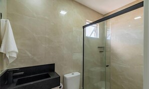 A modern bathroom with a glass shower enclosure, a black sink, and a white towel hanging on the wall. - Comfortable Apartment Near Praia Pereque Cii0602 (Porto Belo)