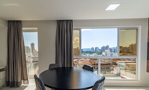 A modern room with a large window, a round table, and two chairs. - Comfortable Apartment Near Praia Pereque Cii0602 (Porto Belo)
