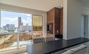 A modern kitchen with a large window, a built-in oven, and a dining area with a black countertop and cushioned chairs. - Comfortable Apartment Near Praia Pereque Cii0602 (Porto Belo)