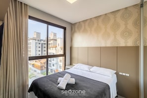 A hotel room with a large window, a bed with white linens, and a patterned wall. - Apt sea View, Pool Condo, 300m to Beach Csd0302 (Bombinhas)