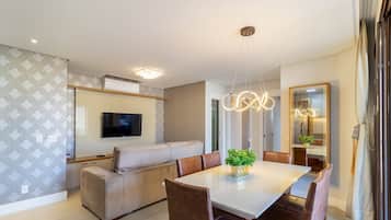 Una sala de estar moderna con un sofá, una mesa de comedor y un televisor montado en la pared.