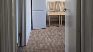 A hallway with a white refrigerator, a wooden bench, and a door. - Cosy Flat near Canary Wharf | Sleeps 6 (London)