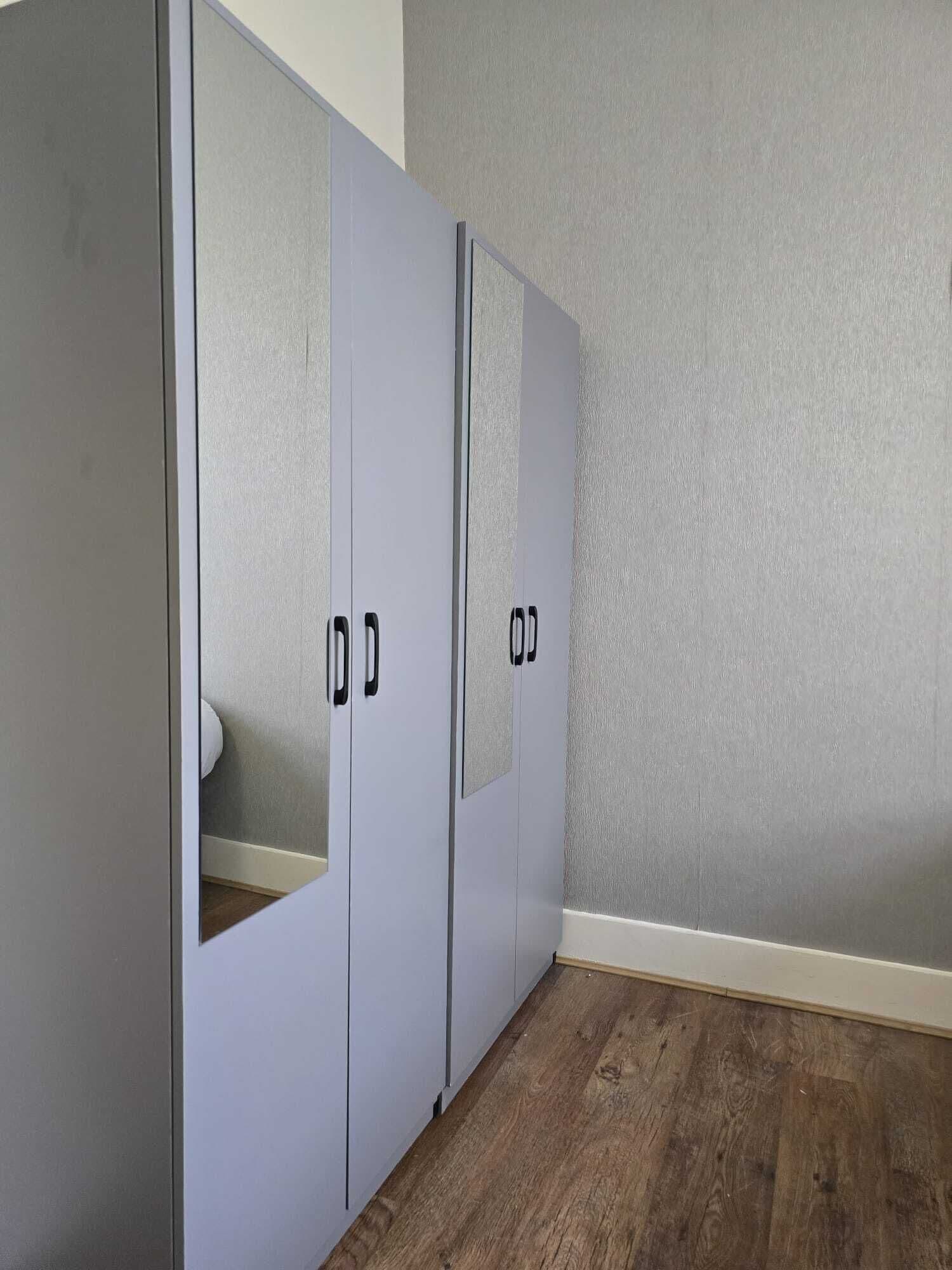 A room with a wardrobe, a mirror, and a textured wall.