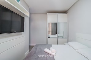 Ein Hotelzimmer mit Bett, Fernseher, Kleiderschrank und Spiegel.