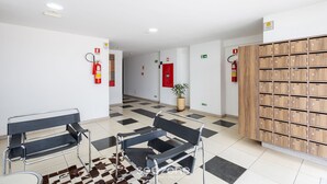 A lobby with a checkered floor, two metal chairs, a wooden storage unit, and a potted plant. - 1BR Apart With Self Check-in, Asa Sul Gdp0010 (Brasília)