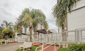 A gated outdoor area with palm trees, a metal staircase, and a building with barred windows. - 1BR Apart With Self Check-in, Asa Sul Gdp0010 (Brasília)