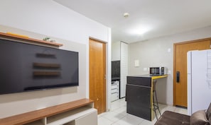 Una cocina compacta con microondas, refrigerador y un pequeño comedor.