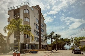Monikerroksinen rakennus, jossa on parvekkeita, suuret ikkunat ja palmu etualalla.
