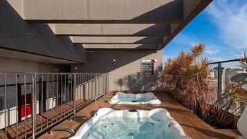 Terraza en la azotea con dos jacuzzis y vistas al horizonte urbano.