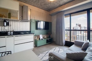 A modern apartment with a kitchen, a flat-screen TV, a sofa, and a large window with a city view. - Comfort in a Condominium With a Pool Idvb2103 (Goiânia)