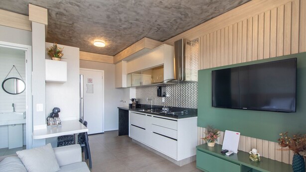 Una cucina moderna con forno a microonde integrato, piano cottura e un grande schermo piatto montato a parete.