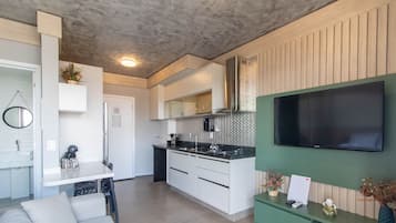 A modern kitchen with a built-in microwave, a stove, and a large flat-screen TV mounted on the wall.