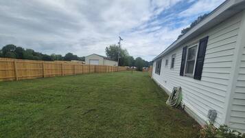 A residential area with a white house, a wooden fence, and a grassy yard.