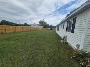 A residential area with a white house, a wooden fence, and a grassy yard.