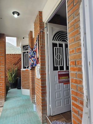 Fachada de ladrillo con una puerta, una ventana con barrotes y un letrero.
