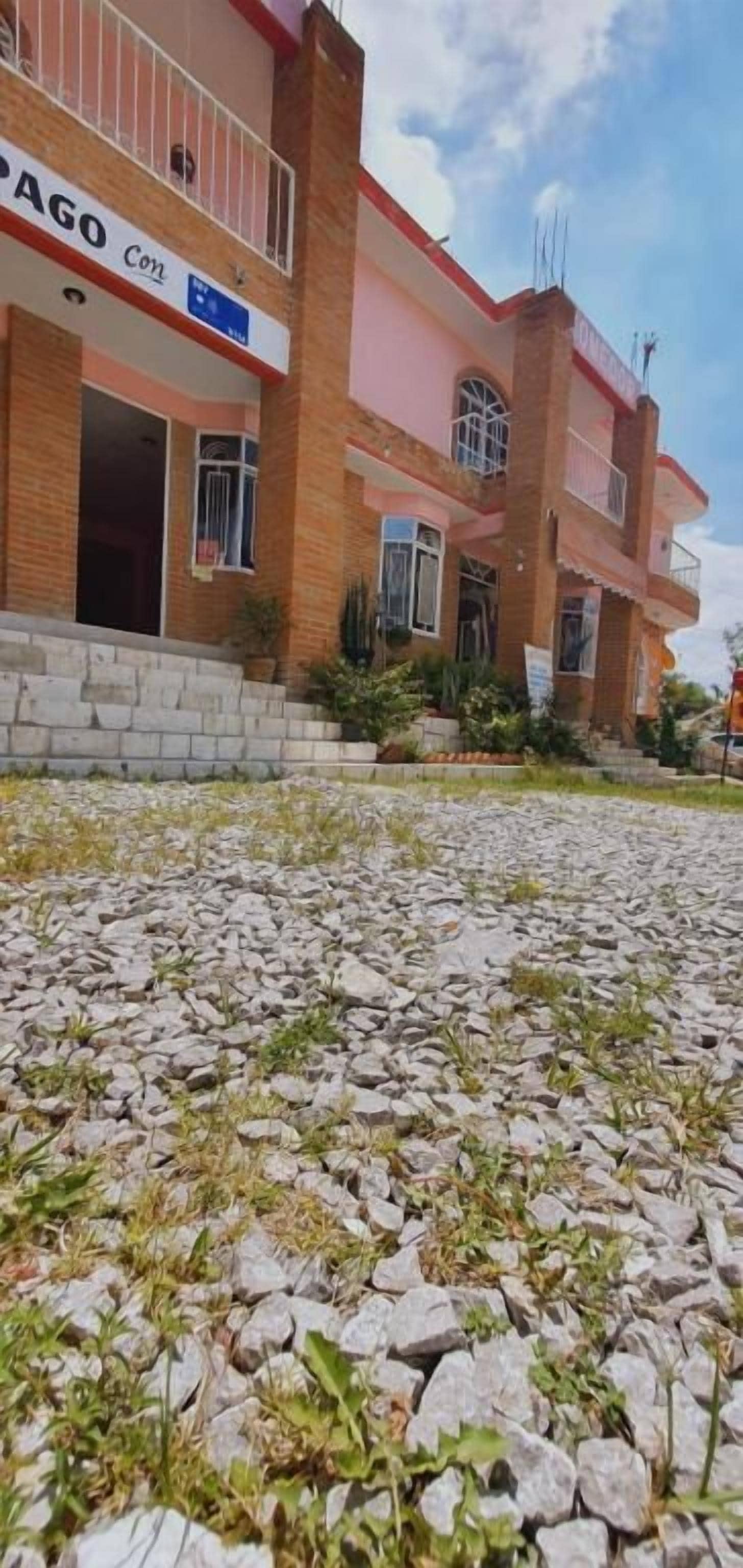 Un edificio de varios pisos con un letrero que dice 'PAGO Con'.