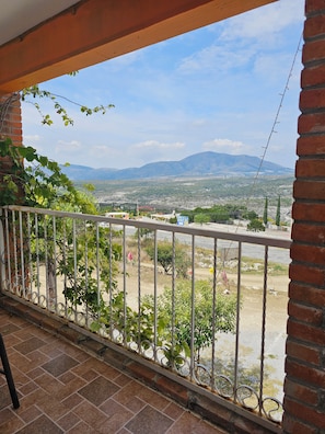 Un balcón con vistas a un paisaje montañoso, un área pavimentada y una carretera.