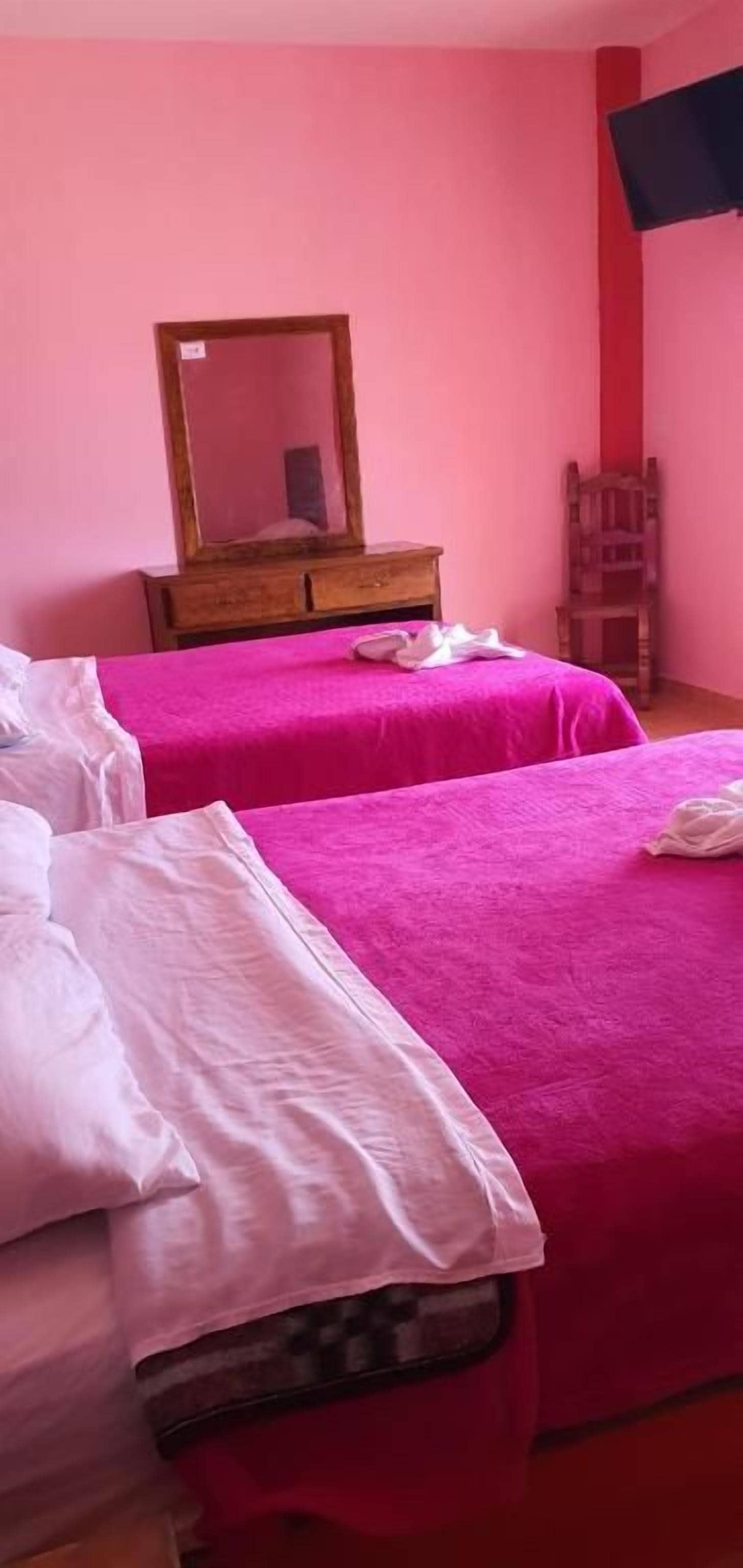 Een kamer met twee bedden, een houten dressoir en een spiegel.