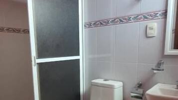 Un baño con inodoro, lavamanos y zona de ducha.